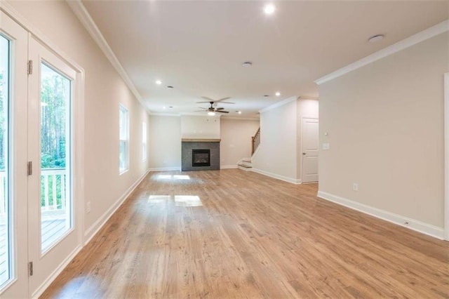 unfurnished living room with ornamental molding, a fireplace, ceiling fan, baseboards, and light wood-type flooring