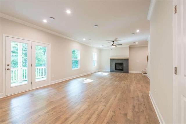 unfurnished living room with ornamental molding, ceiling fan, a glass covered fireplace, light wood-style flooring, and baseboards