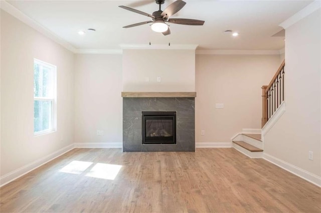 unfurnished living room featuring light hardwood / wood-style flooring, ornamental molding, a tile fireplace, and ceiling fan