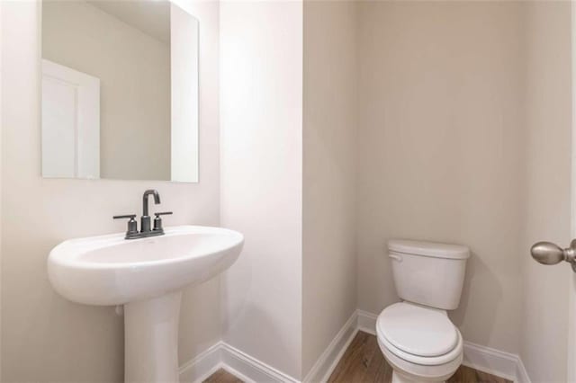 bathroom featuring toilet, baseboards, and wood finished floors