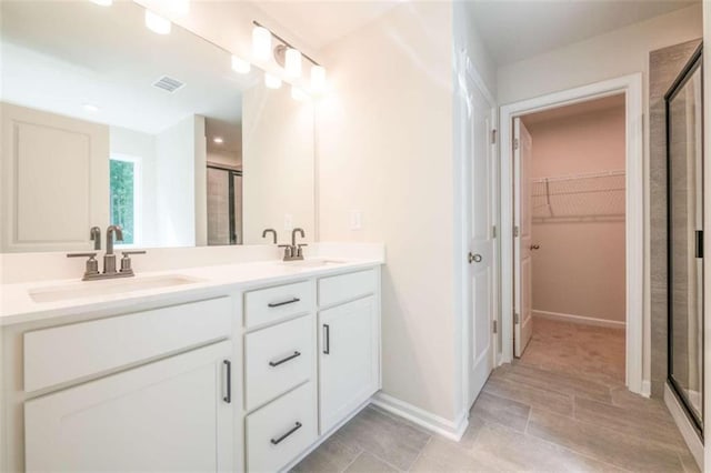 full bathroom featuring a shower stall, a spacious closet, double vanity, baseboards, and tile patterned flooring
