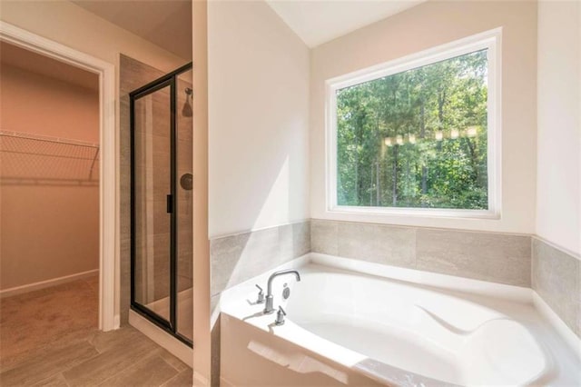 bathroom featuring a stall shower, a spacious closet, and a garden tub