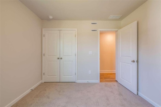 unfurnished bedroom with light colored carpet and a closet