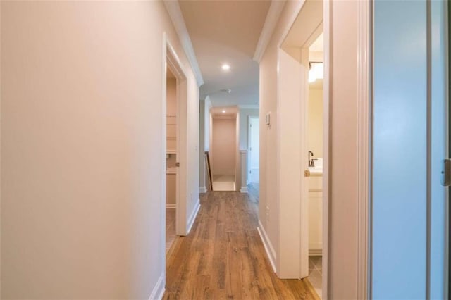 corridor with wood finished floors, ornamental molding, recessed lighting, and baseboards