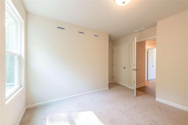 unfurnished room with light carpet and baseboards