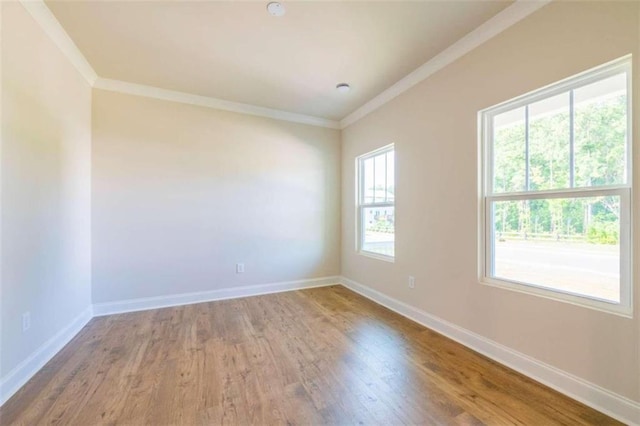 unfurnished room with crown molding, wood finished floors, and baseboards