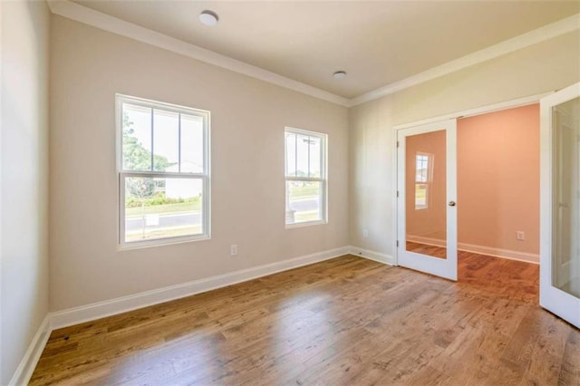 spare room featuring french doors, baseboards, wood finished floors, and ornamental molding