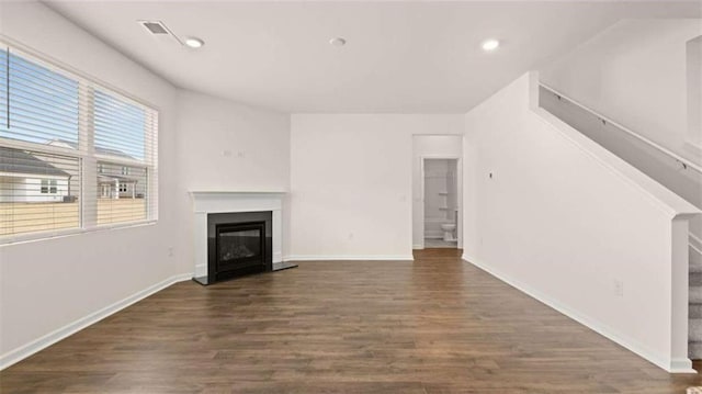 unfurnished living room with a glass covered fireplace, baseboards, and wood finished floors