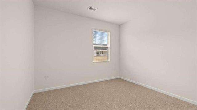empty room featuring visible vents, light colored carpet, and baseboards