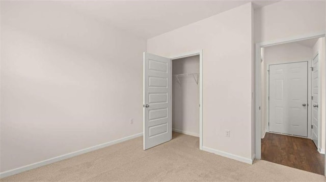 unfurnished bedroom with a closet, baseboards, and light colored carpet