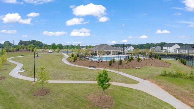 view of community with a pool, a lawn, and fence