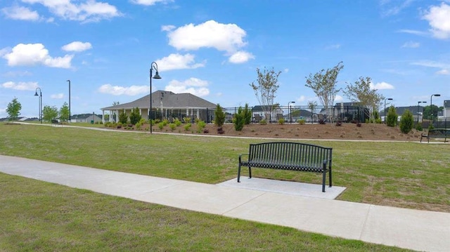 view of property's community with a lawn and fence