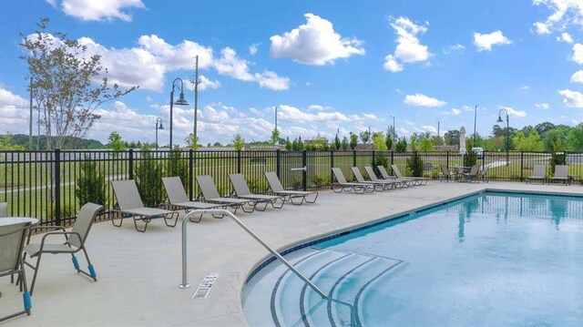 community pool with a patio and fence