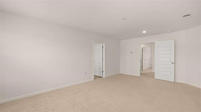 spare room with light colored carpet, recessed lighting, baseboards, and visible vents