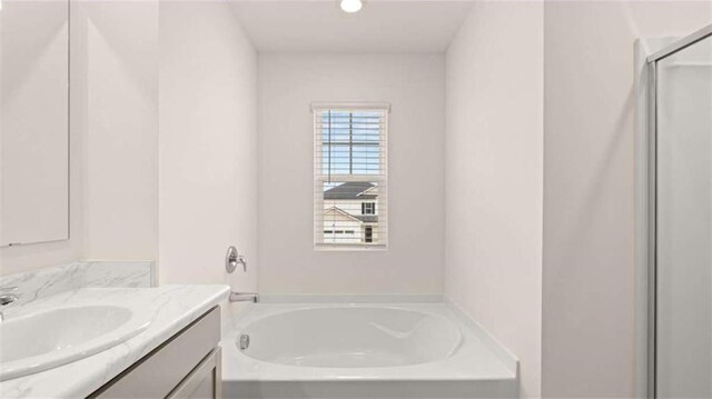 bathroom with vanity, a garden tub, and a stall shower