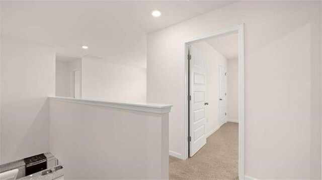hallway with recessed lighting, baseboards, and light colored carpet