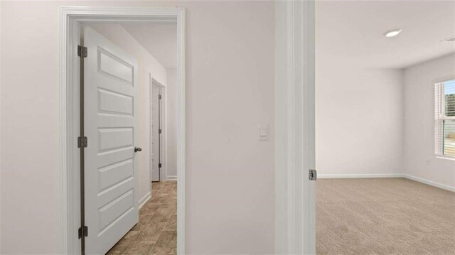 hallway with carpet flooring and baseboards
