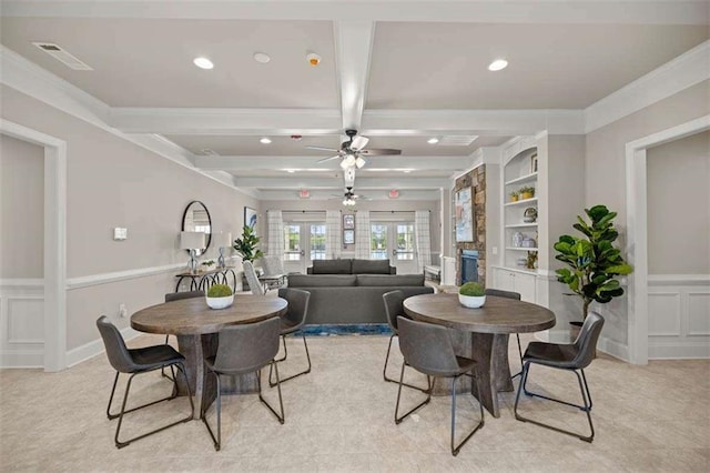 dining space with built in shelves, visible vents, a fireplace, beamed ceiling, and a decorative wall
