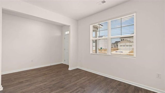 spare room featuring dark wood finished floors, baseboards, and visible vents