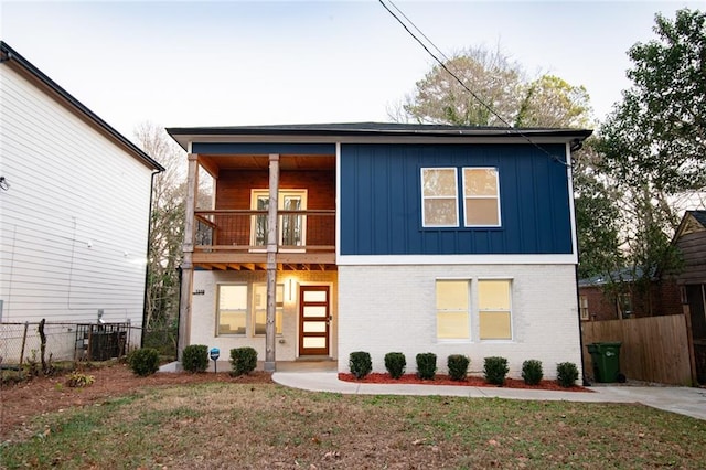 view of front of home featuring central AC, a balcony, and a front yard