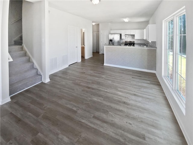 kitchen featuring backsplash, dark wood-type flooring, a peninsula, stainless steel appliances, and white cabinetry