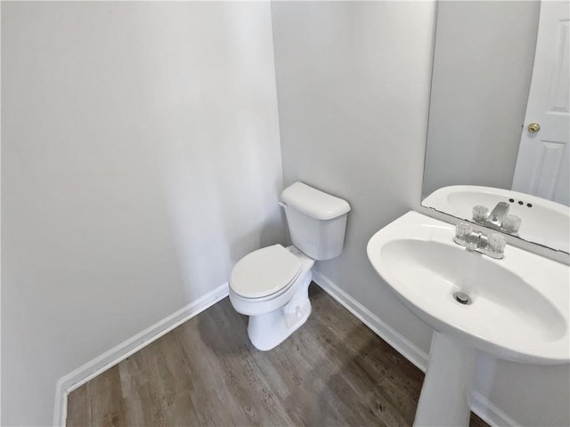 bathroom featuring toilet, wood finished floors, and baseboards