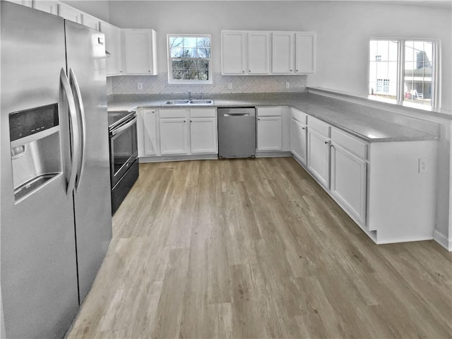 kitchen featuring a sink, stainless steel appliances, light wood-type flooring, and backsplash