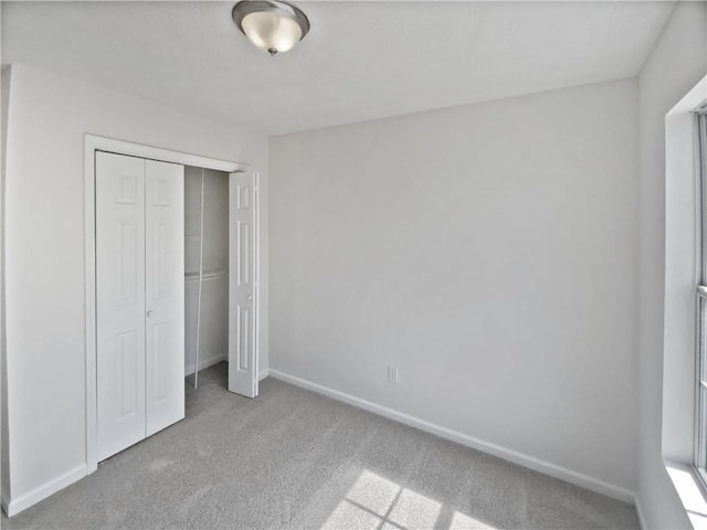 unfurnished bedroom with a closet, baseboards, and carpet