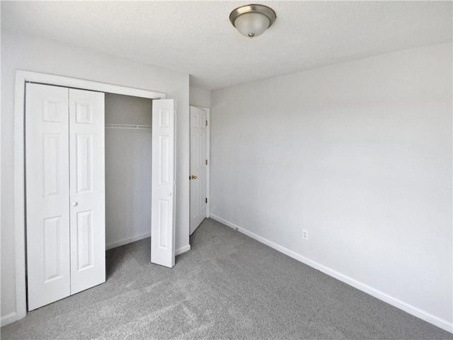 unfurnished bedroom featuring baseboards, carpet floors, and a closet