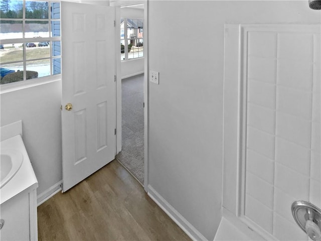 bathroom featuring baseboards, wood finished floors, and vanity