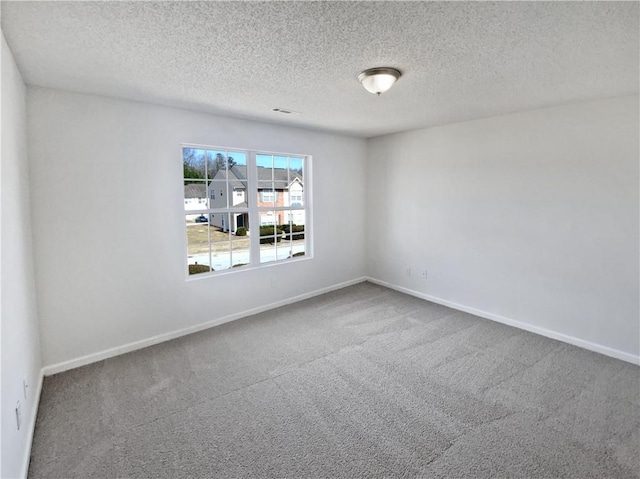 empty room featuring a textured ceiling, baseboards, and carpet