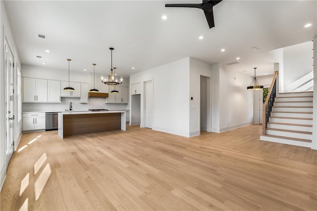 kitchen with white cabinets, a center island, hanging light fixtures, and light hardwood / wood-style flooring