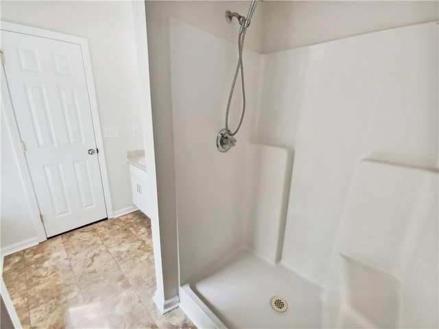 full bathroom with a shower stall and baseboards