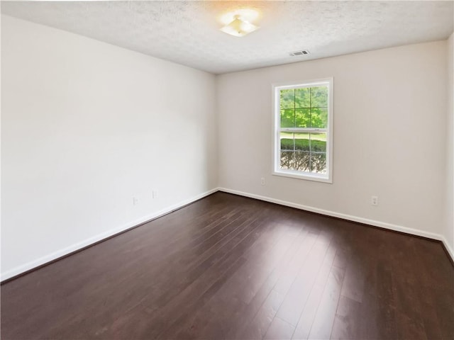 unfurnished room with dark wood-style flooring, baseboards, and a textured ceiling