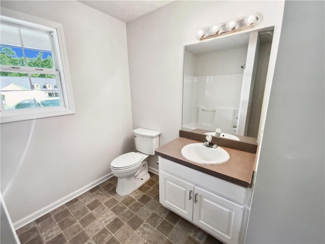 full bathroom with baseboards, a shower, vanity, and toilet