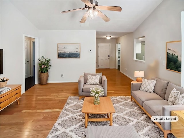 living area featuring ceiling fan, light wood-style flooring, and baseboards