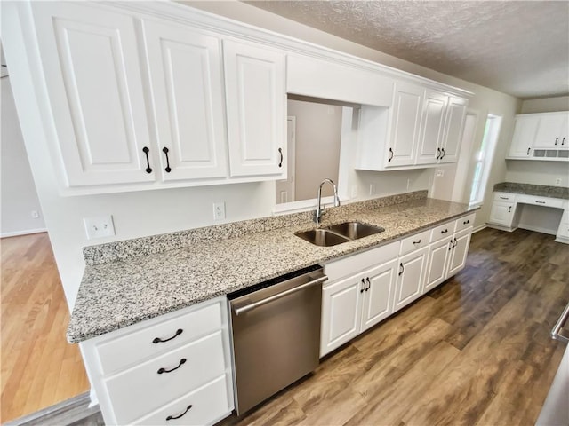 kitchen featuring a sink, stainless steel dishwasher, wood finished floors, white cabinets, and light stone counters