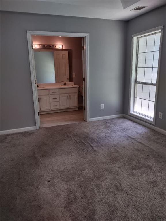 unfurnished bedroom with connected bathroom, multiple windows, and carpet floors