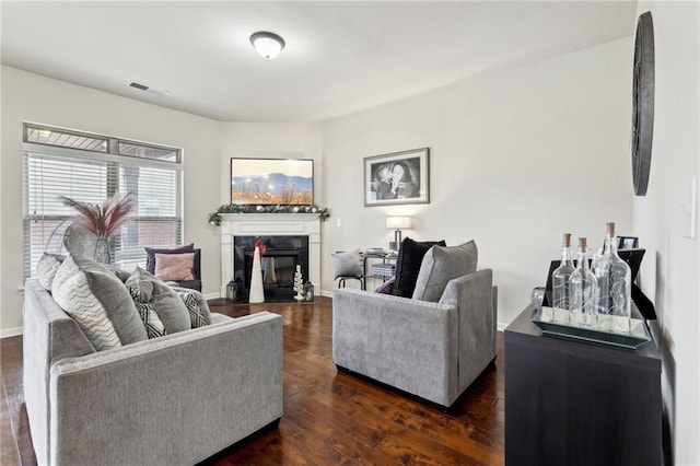 living room with dark wood-type flooring, visible vents, a fireplace, and baseboards