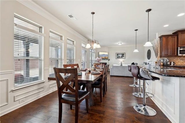 dining space with recessed lighting, crown molding, dark wood-style flooring, visible vents, and an inviting chandelier