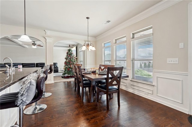 dining room featuring arched walkways, a wainscoted wall, dark wood-style flooring, visible vents, and ornamental molding