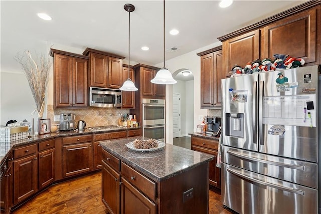 kitchen with a center island, visible vents, hanging light fixtures, backsplash, and appliances with stainless steel finishes