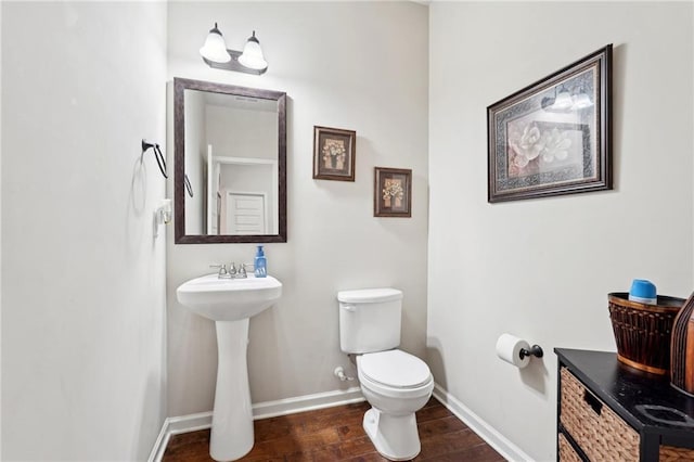 bathroom with a sink, wood finished floors, toilet, and baseboards