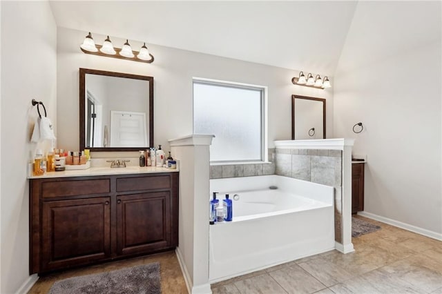 bathroom featuring vaulted ceiling, vanity, a bath, and baseboards