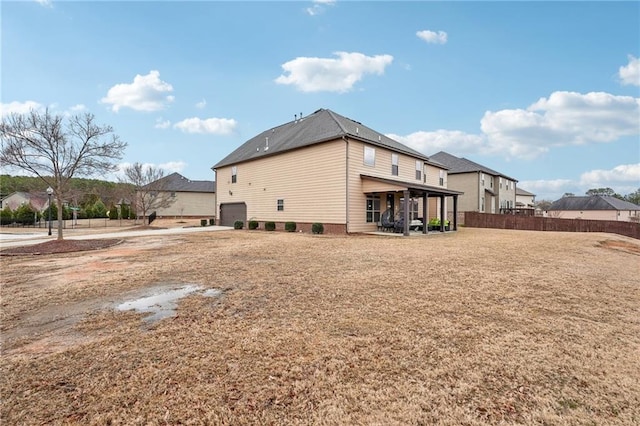 rear view of property featuring a garage, a residential view, and fence