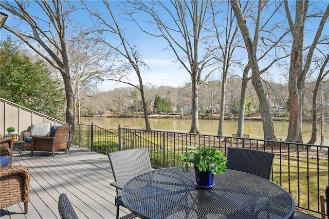 deck with outdoor dining area, a water view, fence, and an outdoor living space