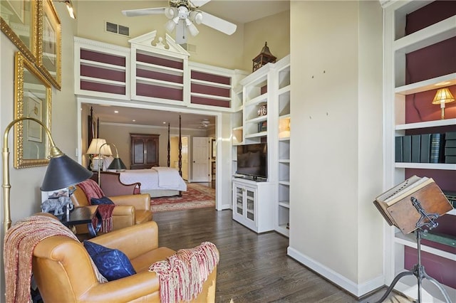 living room with dark wood-style floors, visible vents, ceiling fan, and a high ceiling