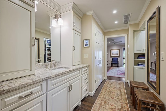 full bath with wood finished floors, vanity, visible vents, a closet, and crown molding