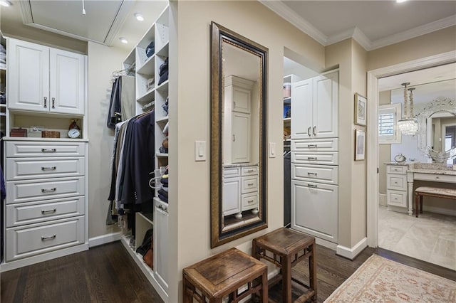 spacious closet with dark wood-style flooring, attic access, and a notable chandelier