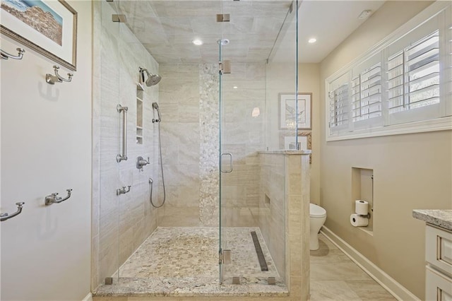 bathroom featuring a stall shower, baseboards, vanity, and toilet